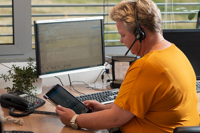 Vrouw zit aan een bureau en controleert gegevens op haar tablet.